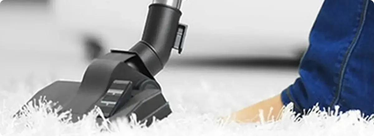 Close-up of a professional vacuuming a white carpet in Miami Beach.