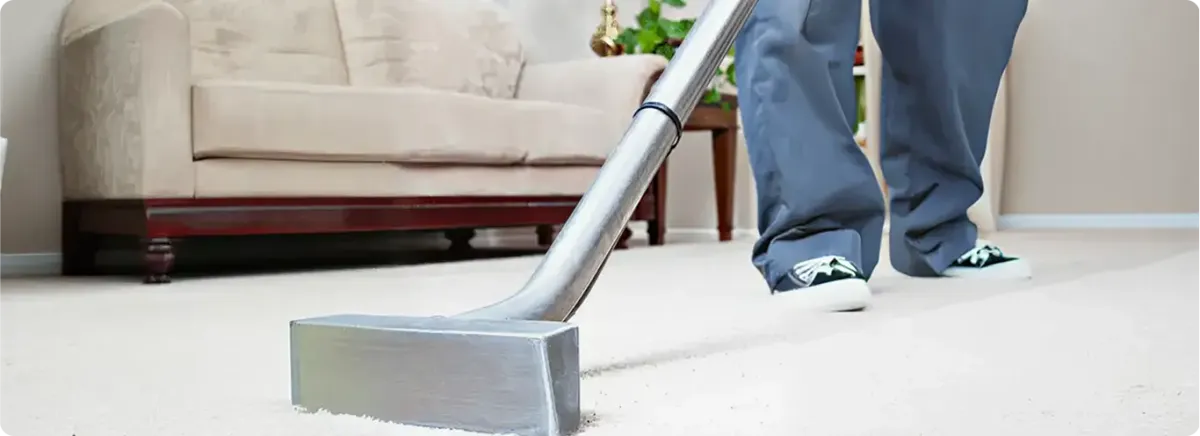 Carpet cleaning technician using a hot-water extraction wand on a light-colored carpet in a living room, Miami, FL.